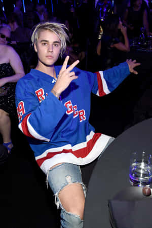 Justin Bieber 在派對上穿著冰球球衣做出和平手勢。 — 小米Pad 8 壁紙
