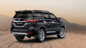 黑色豐田 Fortuner SUV 在沙漠道路上夕陽下