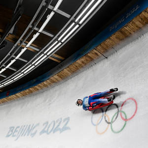 雪橇運動員在北京2022年冬奧會冰道上比賽，冰面上繪有奧運五環。 — 運動 壁紙