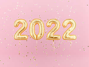 金色2022氣球與五彩紙屑在粉紅色背景上