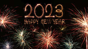 煙火在發光的金色文字周圍爆炸，文字寫著 2023 Happy New Year。 — 煙火 壁紙