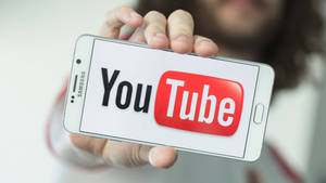 手拿著顯示YouTube應用程式標誌的智能手機。