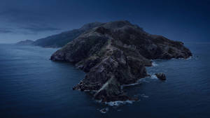 夜晚的岩石島嶼，上方有星星，海浪拍打海岸。