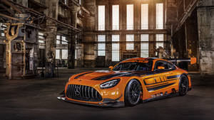 日落時分，生鏽的工業倉庫中的橙色 Mercedes-AMG GT3 賽車。