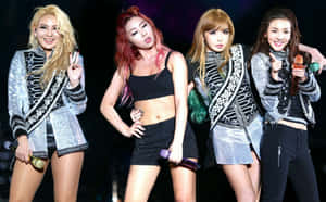 四位女K-pop偶像身穿銀色外套和黑色服裝在舞台上表演。