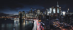 紐約天際線的夜景，建築物燈火通明，交通燈光流動。