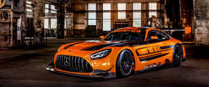 橙色 Mercedes-AMG GT3 賽車在生鏽的工業倉庫中。