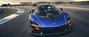 藍色McLaren Senna賽車在黃昏時分的賽道上高速行駛。