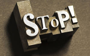 金屬活字塊拼出stop，在棕色表面投下戲劇性陰影