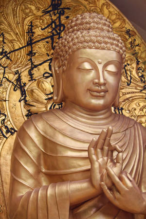 金色佛像雙手合十祈禱，背景是華麗的金色裝飾和書法。