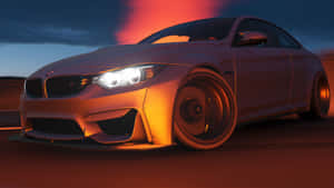 銀色BMW M4轎跑車在黃昏時分疾馳，頭燈發光，天空呈橙色。 — 汽車 4K 壁紙