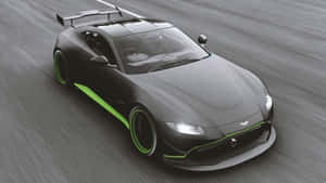 灰色 Aston Martin 跑車帶有綠色飾邊在道路上高速行駛。 — 極限競速：地平線4 壁紙