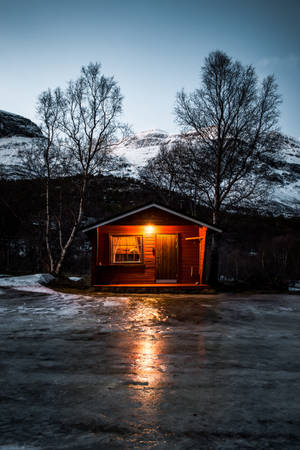 在暮色中，雪景山區裡一間溫暖照亮的木屋。