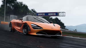 橙色McLaren 720S在潮濕賽道上飄移，有山脈和WAKOS標誌。 — 麥拿侖 GIF 壁紙