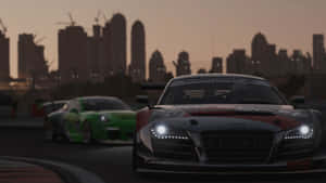 兩輛賽車在黃昏時分的賽道上飛馳，背後是城市天際線。 — Audi R8 GIF 壁紙