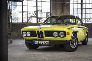 復古黃色BMW 2002 Turbo停放在一個有塗鴉的工業倉庫內。