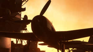 復古戰機在航空母艦甲板上以金色日落為背景形成剪影。 — 微軟模擬飛行 壁紙