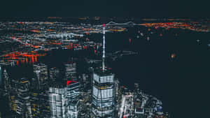 夜晚空中俯瞰城市，發光的摩天大樓和水上發光的橋樑。