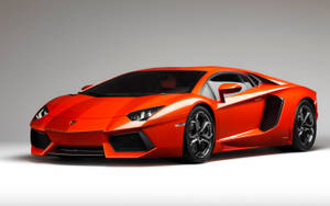 工作室中的橙色林寶堅尼Aventador跑車，配備黑色輪圈和空氣動力學設計。