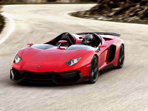 紅色林寶堅尼 Aventador Roadster 在日落時分於蜿蜒道路上奔馳。