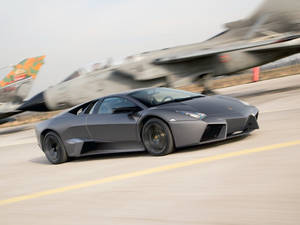 啞光灰色的林寶堅尼 Reventon 在跑道上飛馳經過一架戰鬥機。