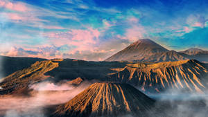 日出時，火山聳立於霧氣瀰漫的山谷之上，天空色彩繽紛。