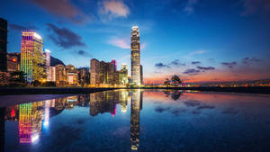 黃昏時分的城市天際線，建築物倒映在水中。