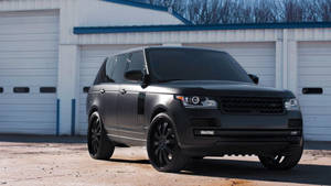 啞光黑色Range Rover Sport停在一棟白色工業建築前。