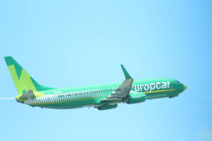 綠色 Europcar 飛機在清澈藍天中飛行