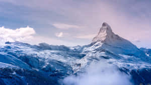 在寧靜的冬日景色中，雪山峰聳立於雲層之上。