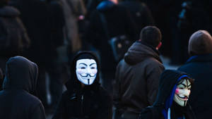 穿著連帽衫的抗議者在夜間戴著發光的蓋伊·福克斯面具。