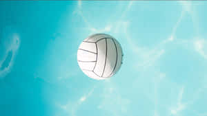 白色排球浸沒在陽光照射的碧綠色游泳池中。