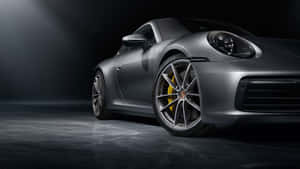 銀色保時捷911跑車，帶黃色制動卡鉗，在黑暗的攝影棚燈光下。