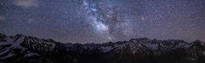 星空下白雪覆蓋的山脈，銀河清晰可見 — 雙螢幕 壁紙