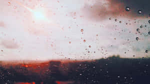窗戶上的雨滴，俯瞰著夕陽下朦朧的城市。