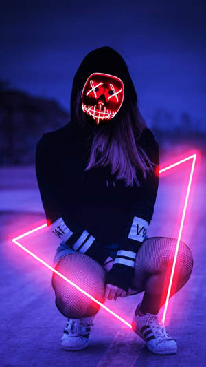 戴著發光面具並在夜間手持霓虹三角形的人。 — 霓虹 壁紙