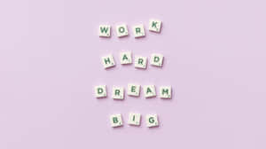 Scrabble 字母塊在薰衣草背景上拼出 work hard dream big
