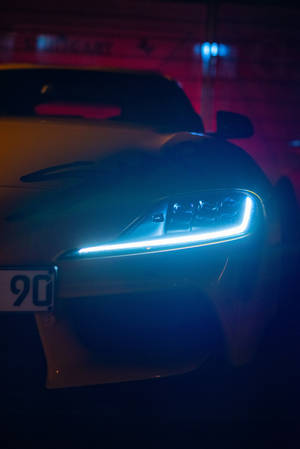時尚跑車在黑暗的霓虹車庫中發出藍色車頭燈。 — 汽車 4K 壁紙