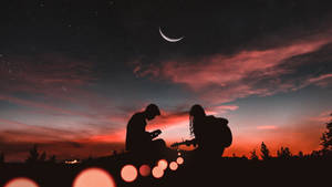 兩個人在黃昏時分在彎月和星星下彈結他。 — 月色夜空 壁紙