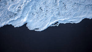 白色的泡沫海浪從上方與深黑色的沙灘相遇。 — 海浪 壁紙