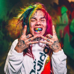 擁有彩虹頭髮和紋身的人做出搖滾手勢。