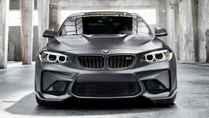 混凝土倉庫內帶金色飾邊的啞光灰色BMW M2跑車。