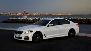 白色BMW轎車在黃昏時停靠在海濱燈塔附近。
