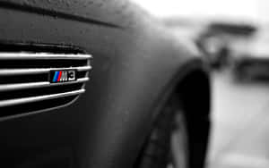 濕透的BMW M3鬼面罩徽章，雨滴附在黑色汽車表面上。