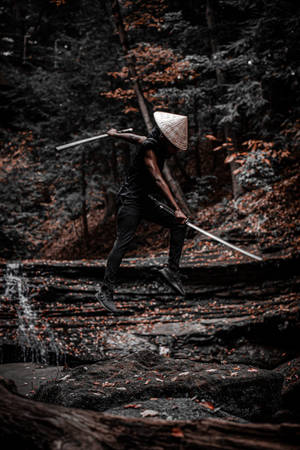 戰士在瀑布附近的秋林中持劍跳躍 — 日本武士 壁紙