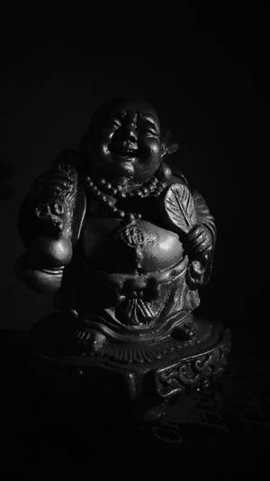 黑白微笑佛像，帶有細緻雕刻和深色背景。