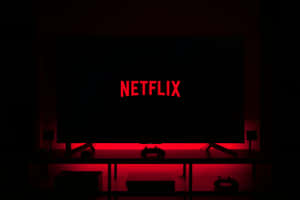 在黑暗的房間中，電視顯示Netflix標誌，發出紅色光芒。 — Netflix GIF 壁紙