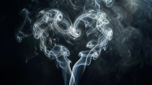 由旋轉煙霧在深色背景上形成的愛心形狀。