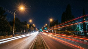 夜晚城市街道，帶有車燈光跡與星空。