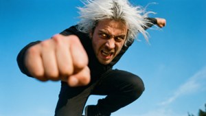 一個白髮男人對著藍天向前揮拳。